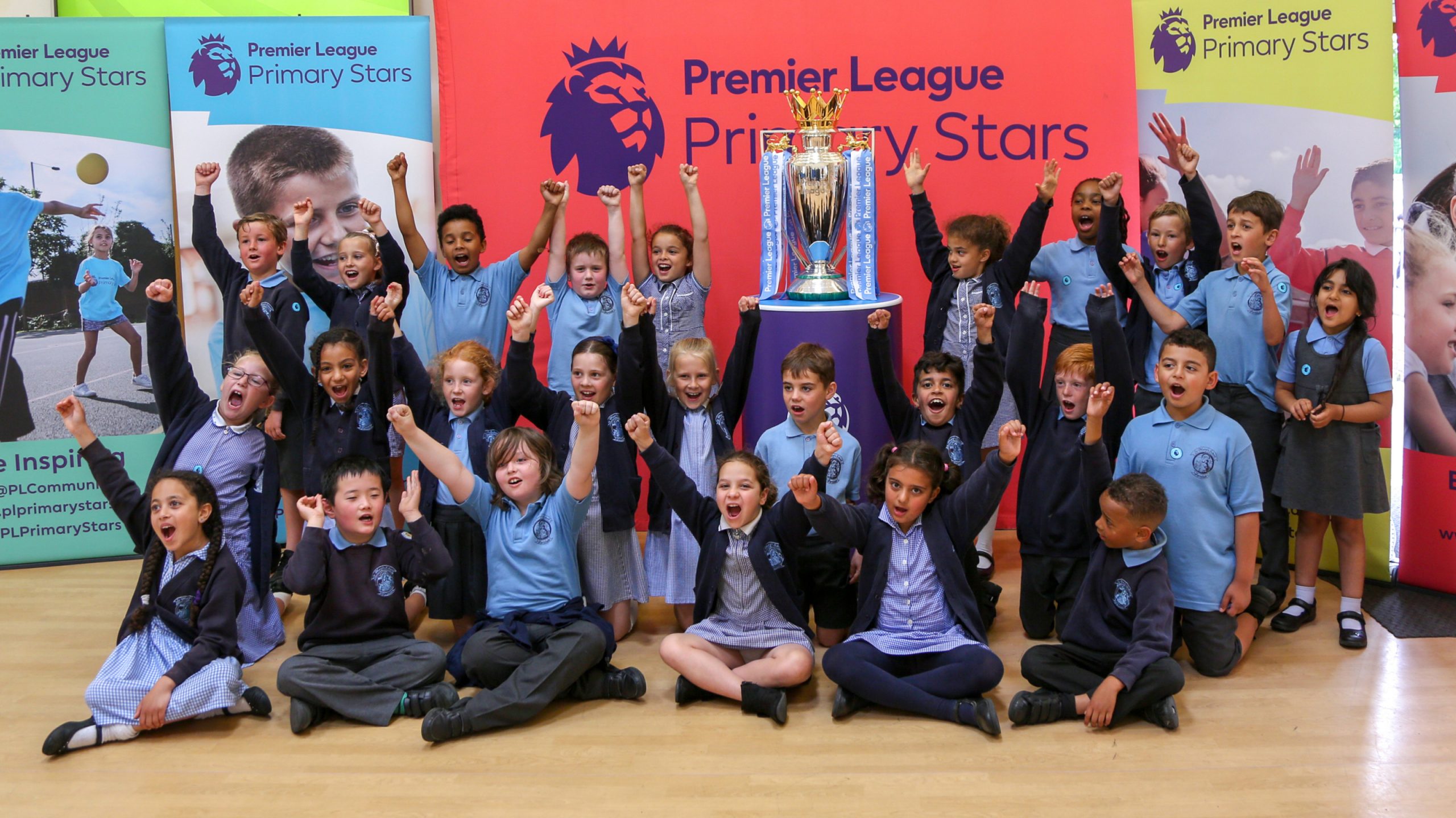 kinds with arms up near a football cup