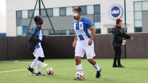 Two Albion players warming up before the game, with the Albion badge looming in the background