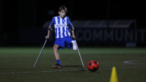 Charlie wearing Albion home kit goes to strike a ball on a 3G pitch.