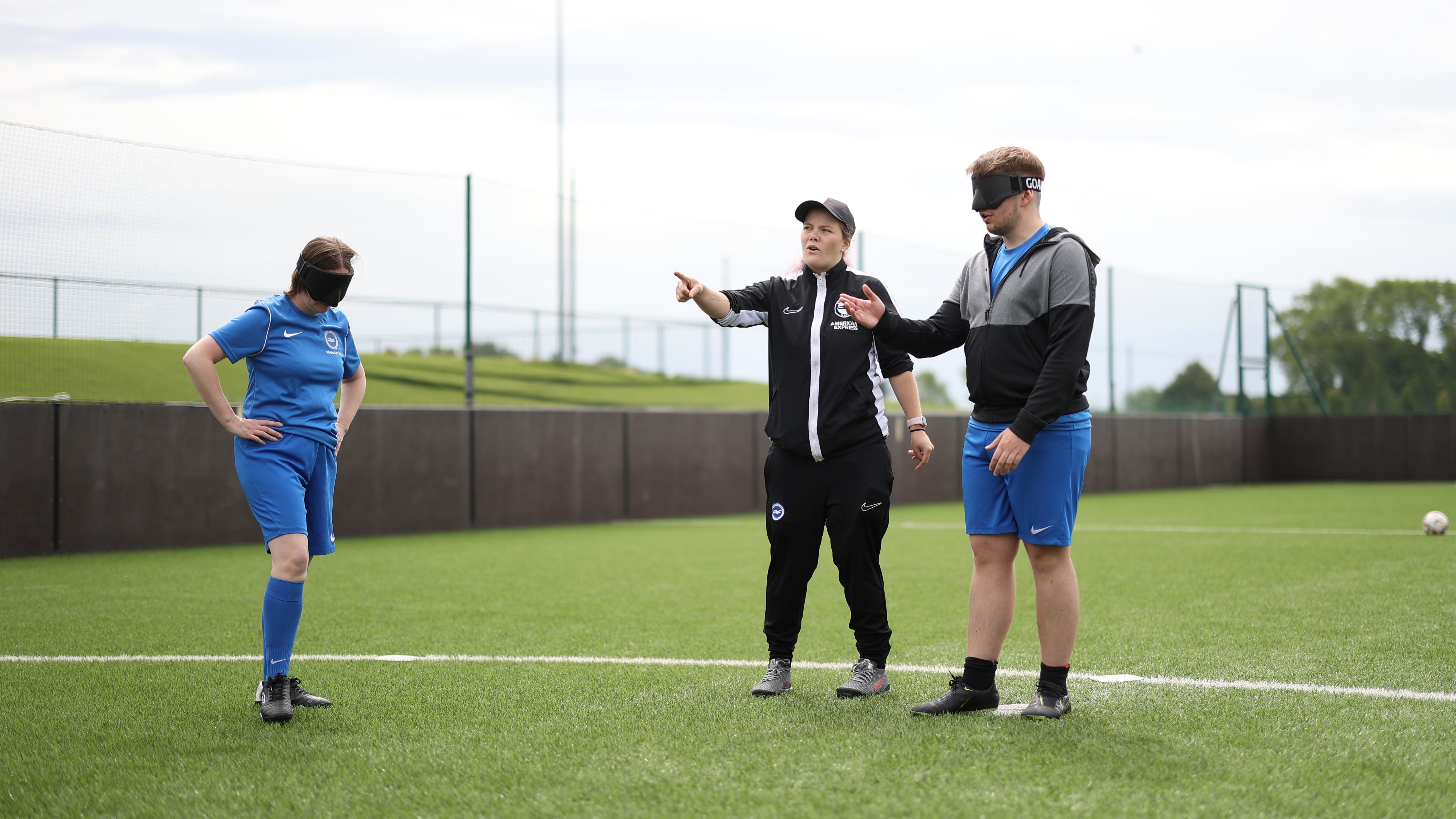 A Foundation coach stands with Alison and Sam giving them instructions.