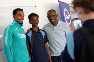 Femi Azeez and Leroy Rosenior have a photo taken with a young person